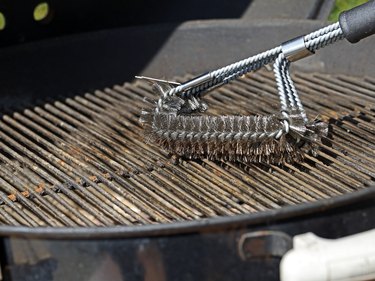 Cleaning a dirty grill grate with a stainless steel grill brush