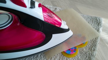 Close-up of pink iron melting through parchment to finish a heart figure made of colorful plastic beads