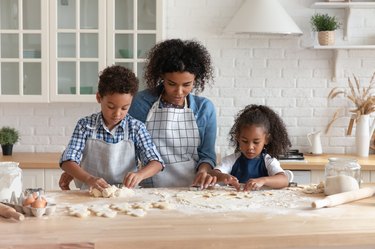 woman teach little adorable children cooking homemade cookies