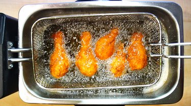 Frying chicken in deep fryer.