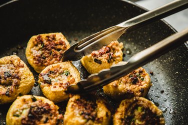 asian woman pan frying tofu with meat stuffing (酿豆腐）-traditional Cantonese food