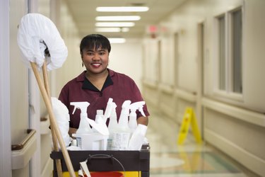 Janitorial worker with cart in hospital hallway
