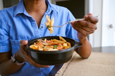 Woman Eats Takeout Pasta and Chicken Dish