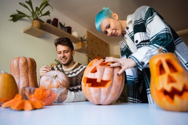 One happy young couple preparing pumpkins for Halloween