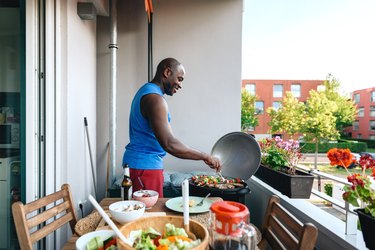 man preparing  barbecue with vegetarian skewers, lamb meat and sausages on electric grill
