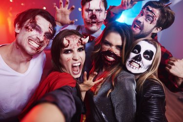 Friends in creepy costumes having fun at Halloween party