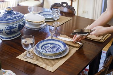 Woman's hands setting table with antique tableware