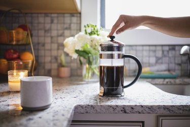 Hand pressing plunger on French press coffee maker