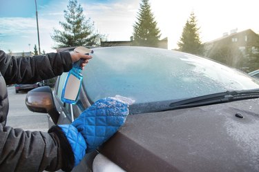 Man uses defroster spray to remove frost