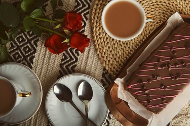 Valentine's day festive breakfast with cherry chocolate cake, coffee cups and aesthetic background of red roses