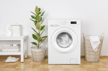 Laundry room interior with washing machine, basket and white wall