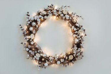 Beautiful Christmas wreath with burning garland hanging on the white wall.