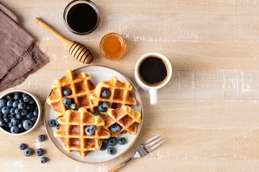 Sweet belgian waffles with blueberries, honey and cup of coffee