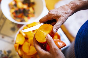 Senior woman cutting  Organic Persimmons in slices