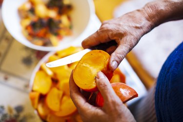 Senior woman cutting Organic Persimmons in slices