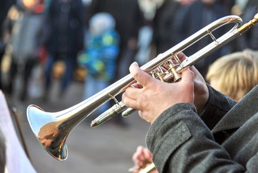 Close-up of an older man who is playing the brass trumpet at a public concert outdoors