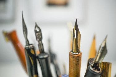 Group of  wooden penholders with calligraphy nibs on a colourful mug on a table with nice background