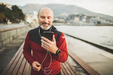 Senior adult athlete share training results online with friends by video communicating on phone