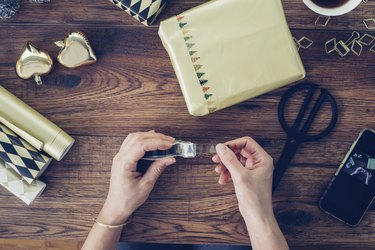 Woman's hands wrapping Christmas present, top view