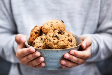 Homemade freshly baked oatmeal cookies in kid`s hands
