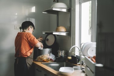 Chinese mother cooking rice in the kitchen using a rice cooker