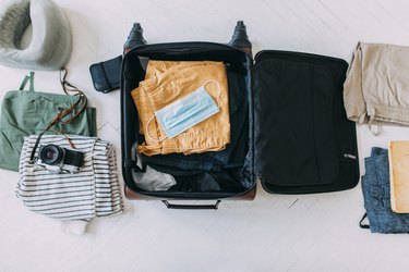 Protective Face Mask Atop a Packed Suitcase, New Normal Concept