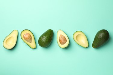 Ripe avocados—some cut, some whole—on mint background