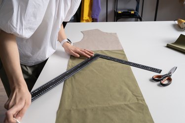 Tailor couturier measuring cloth. Closeup of sewer woman hands hold ruler to cut material for sewing