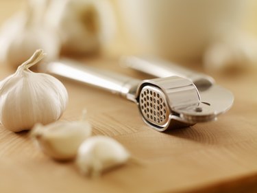 Close up of garlic and garlic press on cutting board