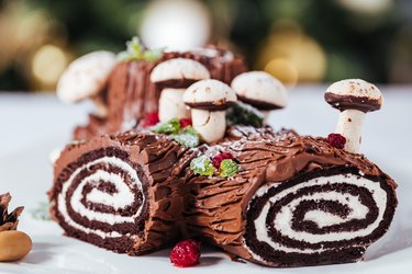 Yule log or bûche de Noël dessert, with Christmas decorations in the background