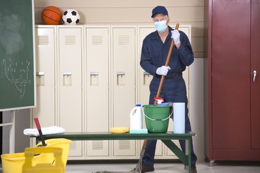 Senior Adult Janitor mops floor in school locker room.