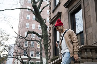 Cheerful young man walking down steps at brownstone