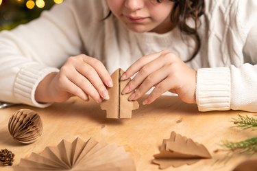 girl makes Christmas tree decorations out of paper with her own hands. step 4