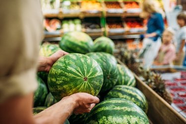 woman picking watermelon in grocery store