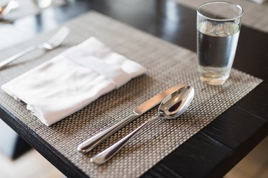 High Angle View Of Cutlery And Napkin On Place Mat At Dining Table
