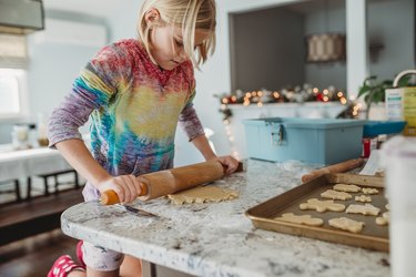 Girl Rolling out dough with Christmas lights in the background