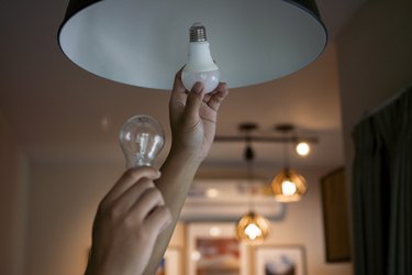 Male hands compare an incandescent light bulb and an LED bulb