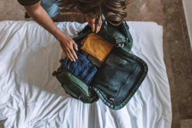 Top view of male traveler packing for a trip, puts clothes in a duffel bag
