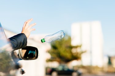 Woman throwing bottle out of car window.