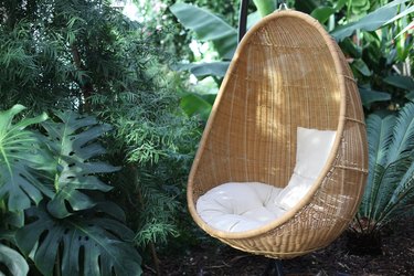 Rattan oval hanging chair witht pillow in tropical plant.