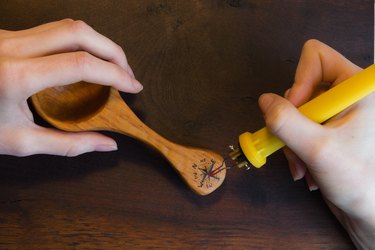 Close-up of female hands making a wind rose sign on wooden spoon.