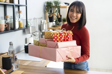 Happy businesswoman carrying gift boxes at home