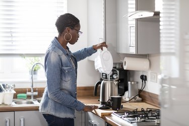 Woman pouring filtered water into kettle in kitchen