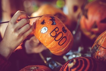 Young girl painting on pumpkin for Halloween