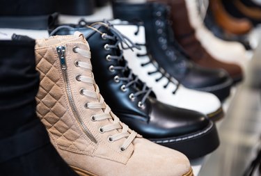 Leather and suede womens ankle boots on shelves in shoe boutique