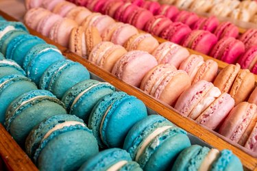 High-angle view of trays of colorful macarons displayed on a wooden stand
