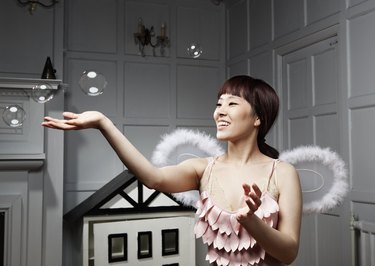 Young woman with angle wings touching bubbles.