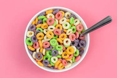 Colored breakfast cereal in a bowl on a pink background.