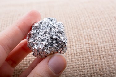 Aluminium foil in the shape of a sphere on  textured background