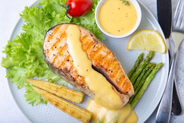 Grilled salmon with asparagus, mini corn and hollandaise sauce.  A traditional dish. Close-up, selective focus